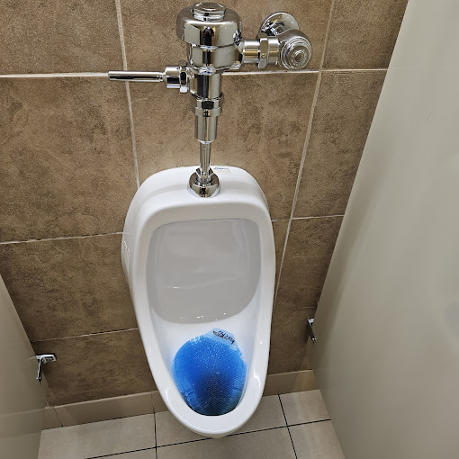 A urinal with a blue ball in it