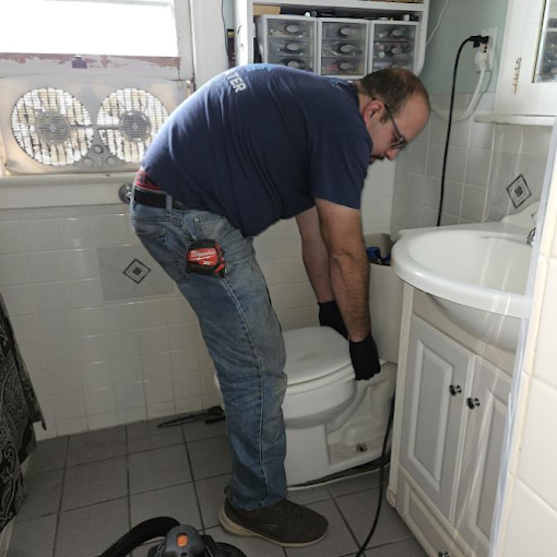 A man is cleaning a toilet in a bathroom